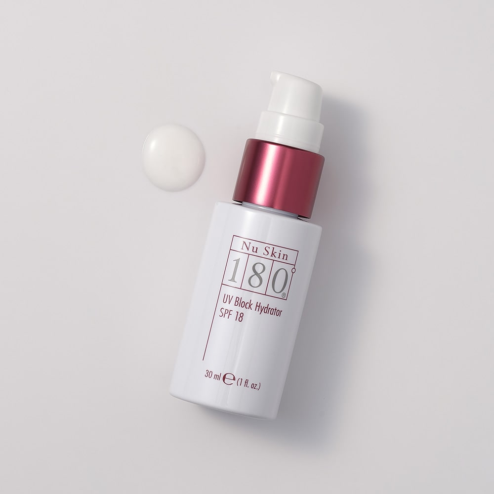 180º UV Block Hydrator SPF 18 von Nu Skin liegt mit abgenommener Verschlusskappe auf glatter Oberfläche. Daneben wurde eine kleine Konsistenzprobe der weißen Feuchtigkeitspflege aufgegeben.