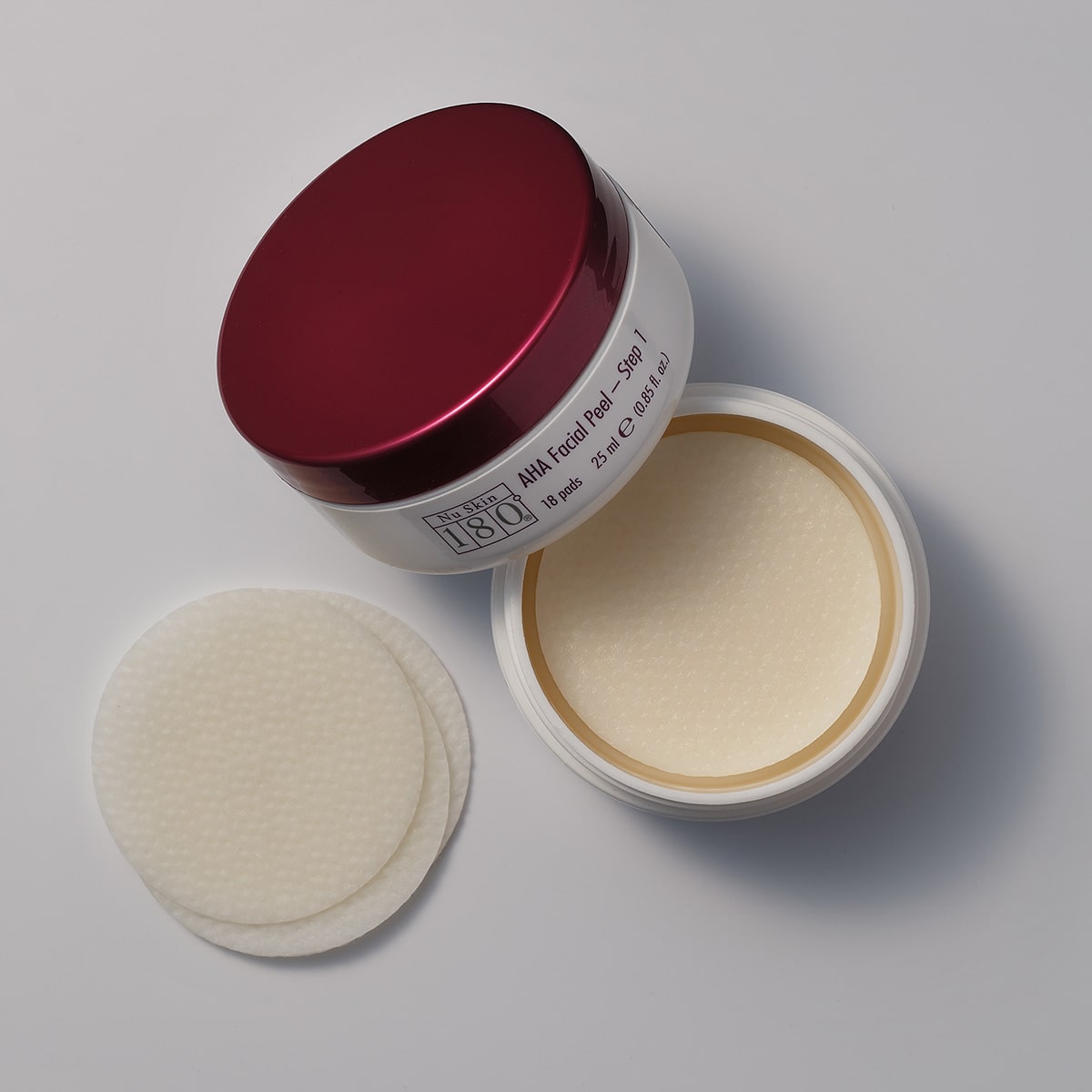 180º AHA Facial Peel and Neutralizer stehen auf grauer glatter Oberfläche. Die Neutralizer Dose ist geöffnet und einige der dünnen cremefarbenen Pads liegen daneben.