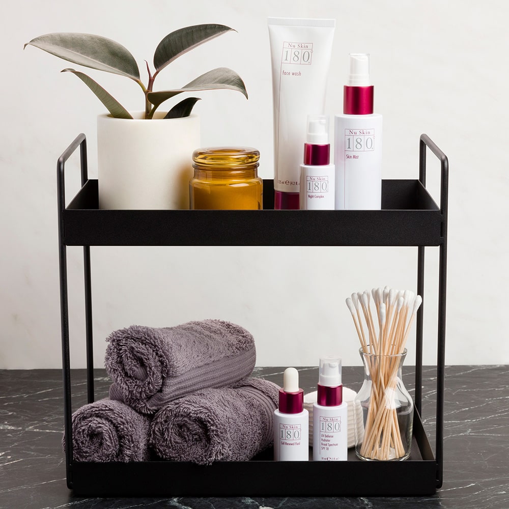 180° Anti-Ageing Skin Care System Produkte stehen in sanitärer Umgebung auf einem Rolltisch neben Handtüchern und Wattestäbchen.