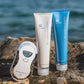 ageLOC Body Shaping Gel und Dermatic Effects Tuben (je 150ml) stehen zusammen mit dem Galvanic Spa auf Felsen. Im Hintergrund erkennt man blaues Wasser.