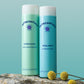 HydraClean Creamy Cleansing Lotion steht neben dem In Balance Toner auf einer Wurzel vor türkisem Hintergrund.
