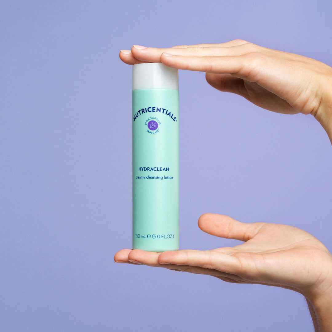 Hände einer jungen Frau präsentieren die HydraClean Creamy Cleansing Lotion von NuSkin.