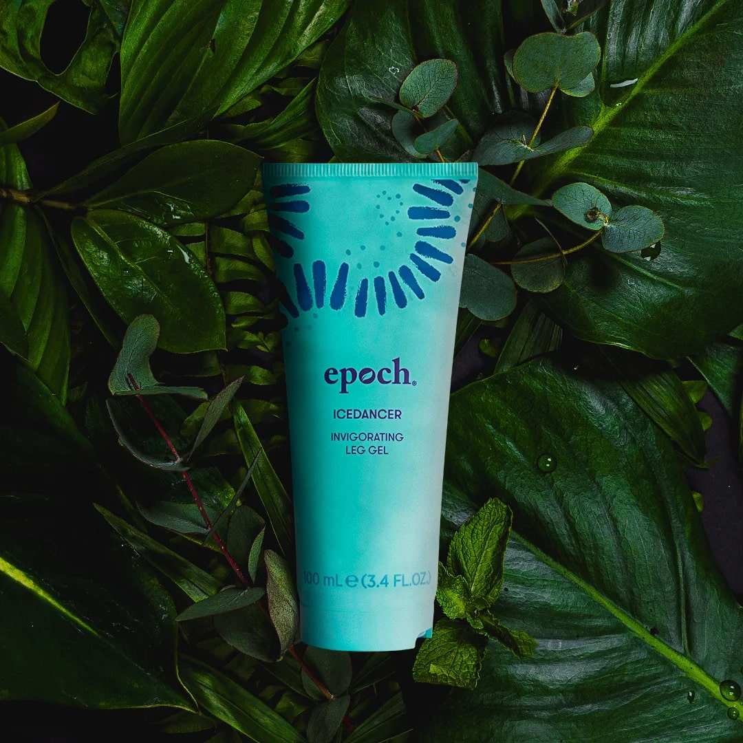 Epoch IceDancer Tube (100ml) von NuSkin liegt geschlossen auf dunkelgrünen Farnblättern.