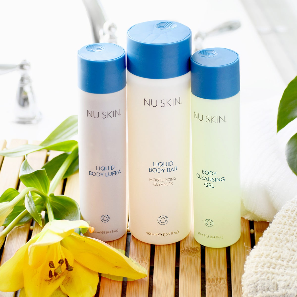 Mehrere NuSkin Basic Produkte zur Körperpflege (darunter Liquid Body Lufra) stehen in sanitärer Umgebung auf einer kleinen Holzmatte.