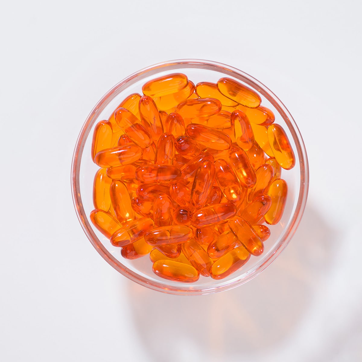 In einer kleinen Glasschüssel liegen orangene Marine Omega Gelkapseln.