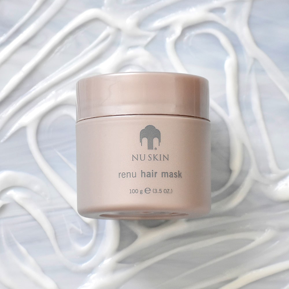 ReNu Haarmaske (Conditioner) liegt auf mar­morner Oberfläche. Darum herum wurde eine großzügige Konsistenzprobe der weißen liquiden Haarmaske aufgegeben.  