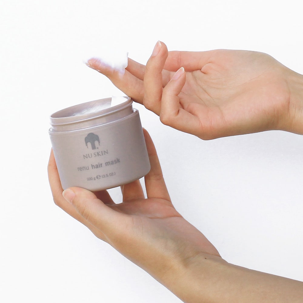 Aus ReNu Hair Mask Behältnis (100g) wird vor weißem Hintergrund mit den Fingerspitzen eine kleine Probe entnommen.