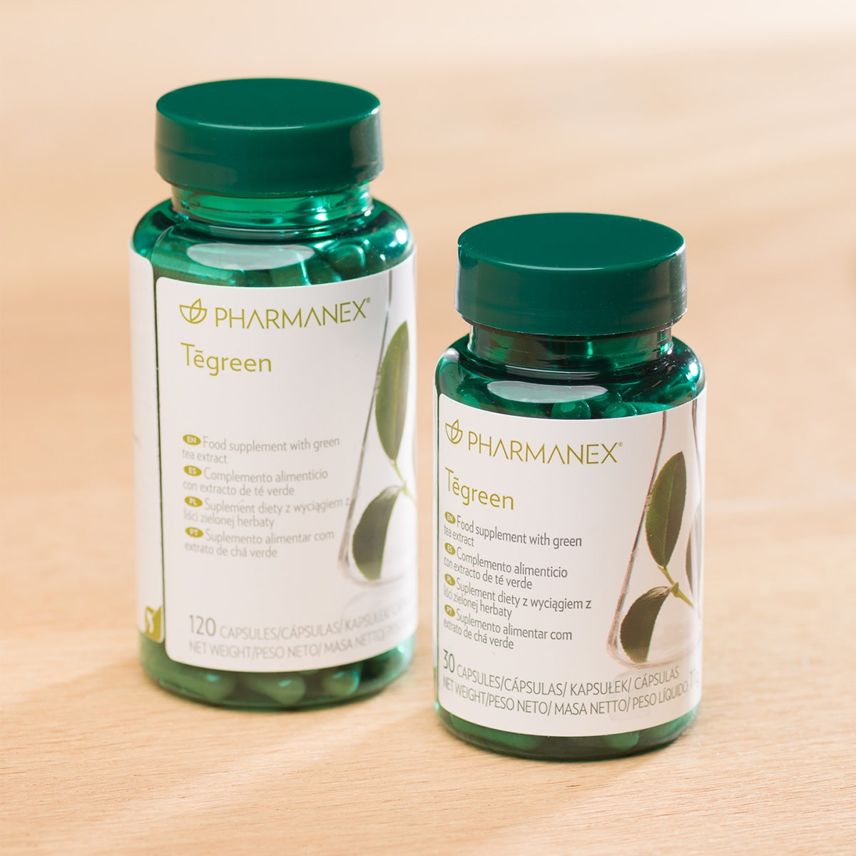Zwei Pharmanex Tegreen Kapselgläser (30 Kapseln, und 120 Kapseln) stehen nebeneinander auf einem Tisch.